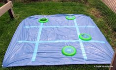 a blue tarp with green frisbees sitting on top of it in the grass