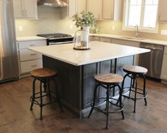 a kitchen island with three stools in front of it