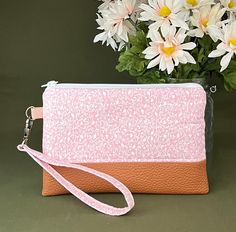 a pink and orange purse with flowers in the background