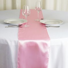 the table is set with white plates and silverware, along with two empty wine glasses