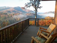 a rocking chair sitting on top of a wooden deck next to a tree filled forest