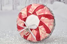 a red and white ornament hanging from a chain on a snow covered ground