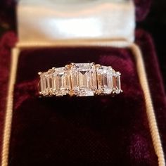 an emerald cut diamond ring sits in a velvet box