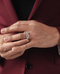 a person wearing a ring with the word love on it's middle finger, standing in front of a red suit