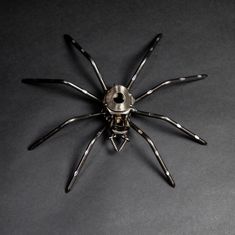 a metal spider sculpture sitting on top of a black table next to a bottle opener