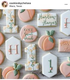 many decorated cookies are arranged on a white table with pink and green accents, including one for the letter h