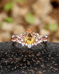 a yellow diamond ring sitting on top of a rock