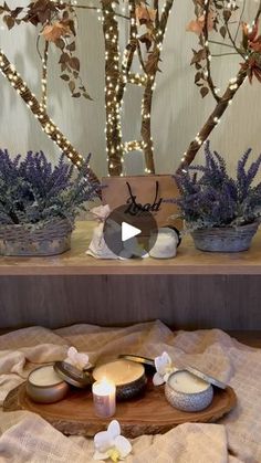 some candles are sitting on a table with lavenders and other items around it in front of a lighted tree