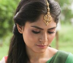 a woman in a green and white sari is looking down at her cell phone