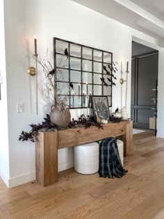 a wooden table topped with lots of vases and plants next to a mirror on the wall