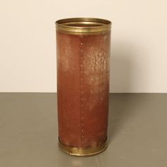 a brown vase sitting on top of a table next to a white wall and floor