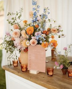 an arrangement of flowers and candles on a table