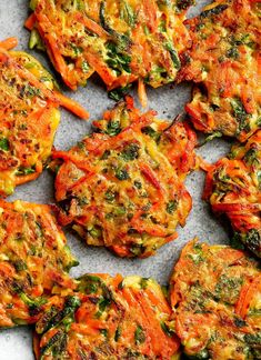 several pieces of vegetable fritters are arranged on a sheet of parchmented paper