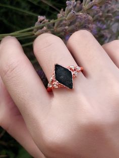 a woman's hand holding a black stone ring