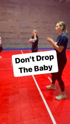 two women standing in a gym with a sign that says don't drop the baby