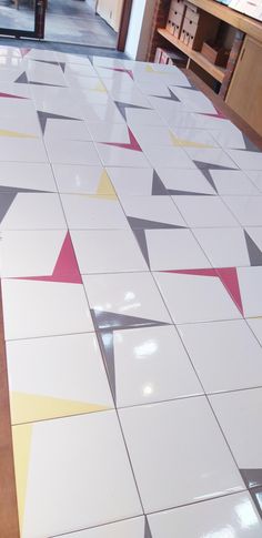 a kitchen floor with white and pink tiles on the ground, in front of cabinets