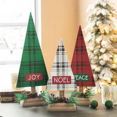 three wooden christmas trees sitting on top of a table next to a small christmas tree