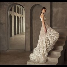 a woman in a white dress is standing on some stairs