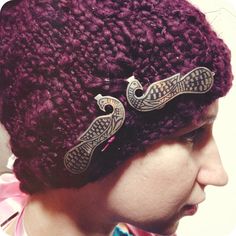 a close up of a person wearing a knitted hat with two birds on it