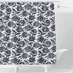 a blue and white shower curtain with an intricate design on the outside, in front of a bathtub