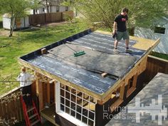 a man standing on top of a roof that is being built in the yard next to a house