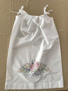 This is a beautiful white cotton/polyester "pillowcase" dress created by Mary that will fit children ages 3 through 8 years old.  It has been created from a brand new 20 x 30-inch white pillowcase that is 60% cotton and 40% polyester.  Mary has carefully and meticulously hand-embroidered the beautiful pastel "Floral Swag" design on the front of the dress using 100% cotton embroidery floss.  The embroidered design measures approximately 12 inches wide x 6 inches tall.  The ribbon straps are adjustable and gather gently around the neckline.  You have the option of white, green, or pink ribbon straps subject to availability.  I currently have one of each color in stock.  Please choose which color you prefer at checkout.   What a beautiful summertime or Easter dress for your child or grandchil Hand Embroidered Dress, Swag Design, Girls Spring Dresses, Girls White Dress, Floral Swag, Pillowcase Dress, Embroidered Pillowcases, School Dresses, Cotton Embroidery