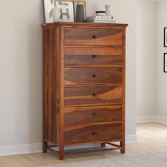 a wooden chest of drawers sitting on top of a hard wood floor next to a white wall