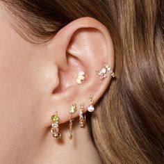 a close up of a person's ear with three different colored stones on it