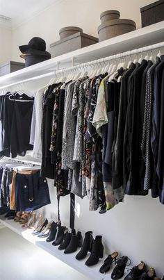 an organized closet with clothes and shoes hanging on the wall next to shelves filled with hats