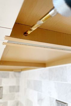 a screwdriver is being used to fix a hole in the wall above a sink