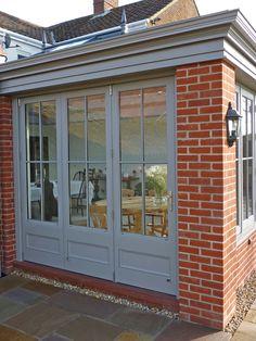 a brick building with two doors and windows on the side of it, next to a patio