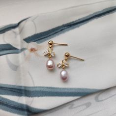 Our cute mini bow pearl earrings are made with natural freshwater pearls, zircon bow knot and 14k gold-plated studs which are good for delicate ears. Size: approx. 0.25" wide and 0.825" long Delicate Pearl Earrings With Cubic Zirconia For Gift, Delicate Cubic Zirconia Pearl Earrings For Gift, Elegant Pink Bow Jewelry Gift, Elegant Pink Bow Jewelry For Gift, Pearl Embellished Cubic Zirconia Earrings As Gift, Gold Pearl Earrings With Bow For Gift, Gold Pearl Earrings With Bow As Gift, Pearl Charm Earrings With Cubic Zirconia As Gift, Elegant Gold Jewelry With Pink Bow