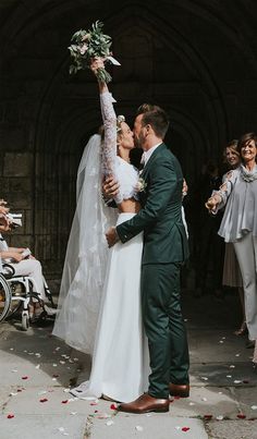 a bride and groom kiss as they walk down the aisle with their guests in wheelchairs