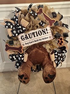 a teddy bear sitting in front of a door with a dog bone wreath on it