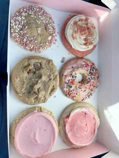 a box filled with lots of different types of doughnuts and frosted cookies