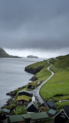 the road is going down to some houses on the side of the hill by the water