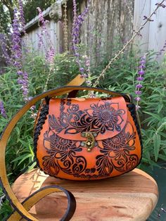 "Beautiful, embossed, genuine orange leather hand tooled floral crossbody purse, skillfully made by Artisans in Mexico using the \"cincelada\" technique. Latch closure and adjustable strap. Includes a storage bag to protect your purse when not in use. Dimensions: 8\" L x 4\" W x 6\" H. (small sized purse). It will fit the standard size phones, and a small wallet, keys and chapstick and or travel sized products, but not an oversized phone (max, plus, etc). Please check measurements if you have any concerns about sizing before purchasing. Imported from Mexico, they are a continuation of the fine craftsmanship established in that country going back hundreds of years with carved leather saddles. These beauties are not like the more common stamped products that can be mass produced cheaply and Mexican Made Purse, Cottage Fashion, Mexican Purse, Skelita Calaveras, Mexican Bag, Purse Handmade, Floral Purse, Leather Carving, Hand Tooled Leather