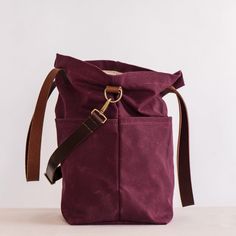 a purple bag sitting on top of a white table next to a brown leather strap