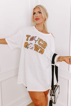 - Football, but make it fabulous with this shimmering tee! Its unique sequined design makes it a perfect addition to any sporty fashionista's game day collection. Stay at the top of the tailgate game with this sporty-chic piece! - Unlined 100% cotton material - A sequined white, black, gold, and brown hued 'TOUCHDOWN' design featuring footballs, a goal post, and a helmet - A crew cut neckline - Short, loose sleeves - A relaxed silhouette that ends in a straight hemline - This piece is perfect fo White Sports Fan Top For Cheerleading, Trendy White Top For Game Day, White Team Spirit T-shirt For Fall, White T-shirt For Game Day In Fall, White Graphic Print Top For Cheerleading, Short Sleeve Tops With Glitter Print For Game Day, White Letter Print Tops For Cheerleading, White Sports Fan Top For Fall, White Tops For Fall Sports Fans