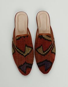 a pair of slippers with an embroidered design on the front and back, sitting on a white surface