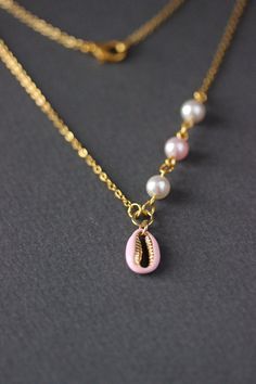 This dainty summer beach style necklace was made of delicate light pink enamel cowrie shell gold tone stainless steel charm, finest quality European crystal pearl coated white and light pink 6 mm beads, gold tone steel jumping rings and gold tone stainless steel chain with gold tone lobster claw. The chain is from lead free & nickel free metal. The length of necklace is 47.5 cm or 18.5 inches. Shell bead size: 9x13 mm. Other necklaces of my shop you can see here: https://www.etsy.com/shop/Na Dainty Necklaces For Vacation, Summer Dainty Pearl Chain Jewelry, Summer Gold Pearl Necklace With Pendant, Gold Necklace With Pearl Pendant For Summer, Dainty Shell Necklace For Summer Beach, Gold Necklaces With Pearl Charm For Summer, Gold Pearl Necklace For Summer, Summer Gold Pearl Necklace, Dainty Clavicle Chain Necklace For Beach