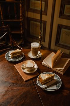 two plates with slices of cake on them next to a cup of coffee and an open book