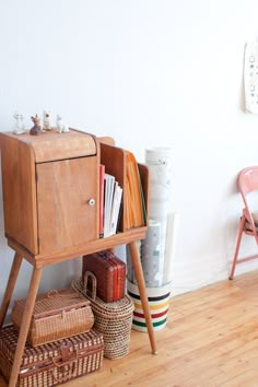 a wooden cabinet sitting on top of a hard wood floor next to a chair and table