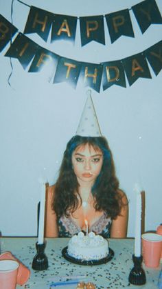 a woman sitting at a table with a birthday cake and candles in front of her