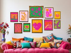 a living room filled with lots of colorful art on the wall above a pink couch