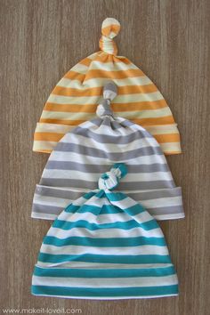 three baby hats sitting on top of a wooden table