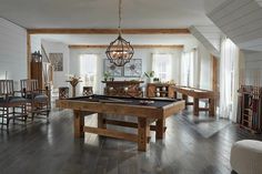 a pool table in the middle of a living room with chairs and tables around it