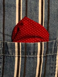 a red polka dot tie sticking out of the pocket of a jean jacket with stripes