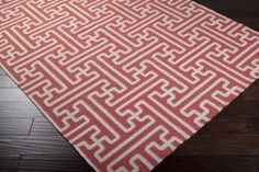 a red and white area rug on a wooden floor with dark wood floors in the background