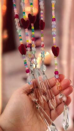 a person holding some beads in their hand with other beads on the string and necklaces hanging from them